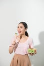 Portrait of a happy playful girl eating fresh salad from a bowl and winking isolated over white background Royalty Free Stock Photo