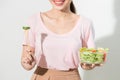 Portrait of a happy playful girl eating fresh salad from a bowl and winking isolated over white background Royalty Free Stock Photo