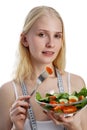 Portrait of a happy playful girl eating fresh salad from a bowl and winking isolated over white background Royalty Free Stock Photo