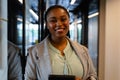 Portrait of happy plus size african american casual businesswoman with tablet in office corridor Royalty Free Stock Photo