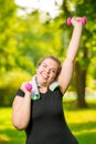 portrait of happy plus size model with dumbbells during workout