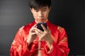 Portrait of happy positive handsome young Asian business man in red Chinese clothes, Qipao or Cheongsam is smiling, using Royalty Free Stock Photo