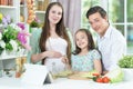Happy pregnant woman with husband and daughter preparing salad together Royalty Free Stock Photo