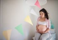 Portrait of happy pregnant woman indoors at home, touching her belly. Royalty Free Stock Photo