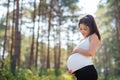 Portrait of happy pregnant woman outdoors in nature, touching her belly. Royalty Free Stock Photo