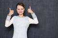 Portrait of happy pretty blond girl wearing jumper showing thumbs up