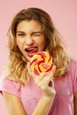 Portrait of a happy pretty girl holding sweet candy over pink ba Royalty Free Stock Photo