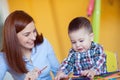 Portrait of happy pretty mother with her toddler son drawing Royalty Free Stock Photo