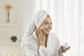 Smiling beautiful young woman applying face cream while doing her skin care routine Royalty Free Stock Photo