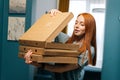 Portrait of happy pretty young woman open box of hot pizza standing at entryway on apartment, looking inside. Royalty Free Stock Photo