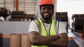 Portrait of happy professional African American male engineer wearing safety hard hat standing and arms crossed in factory Royalty Free Stock Photo