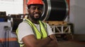 Portrait of happy professional African American male engineer wearing safety helmet standing and arms crossed in factory industry Royalty Free Stock Photo