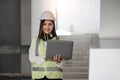 Portrait of Happy professional construction engineer woman holding laptop and wearing the safety helmet at the building Royalty Free Stock Photo