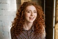 Portrait of happy redhead young woman near window