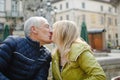 Portrait of happy romantic couple with age difference kissing outdoors in the ancient city during early spring or autumn