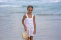 Portrait of a happy Russian little girl in a white dress and hat on a background of the sea. The child walks in the fresh air. Royalty Free Stock Photo