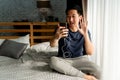 Portrait of happy 30s aged Asian man in casual clothing making facetime video calling with smartphone at home. He`s