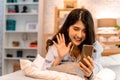 Portrait of happy 20s aged Asian woman in casual clothing making facetime video calling with smartphone at home. She`s Royalty Free Stock Photo