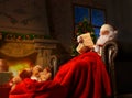 Portrait of happy Santa Claus sitting at his room at home near Christmas tree and reading Christmas letter or wish list.