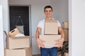 Portrait of happy satisfied man wearing white T-shirt standing with cardboard boxes with belongings, unpacking packages with stuff Royalty Free Stock Photo
