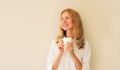 Portrait of happy satisfied smiling young woman enjoying hot tasty cup of coffee or tea in early morning at home