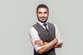 Portrait of happy satisfied and successful handsome bearded man in white shirt and waistcoat standing with folded arms and looking Royalty Free Stock Photo