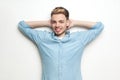 Portrait of happy satissfied and successful handsome young man in light blue shirt standing, raised arms holding his head and Royalty Free Stock Photo