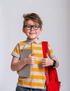 Portrait of happy school boy with backpack isolated against white background. Smiling face in glasses. Blond child in Royalty Free Stock Photo