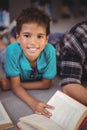 Portrait of happy schoolboy reading book in library Royalty Free Stock Photo