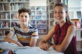 Portrait of happy schoolboy sitting with his classmate in library