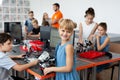 Portrait of a happy schoolgirl girl in a robotics class, she holds a robot assembled from plastic parts programmed on a