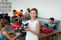 Portrait of a happy schoolgirl girl in a robotics class, she holds a robot assembled from plastic parts programmed on a