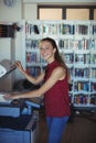 Portrait of happy schoolgirl using Xerox photocopier in library Royalty Free Stock Photo