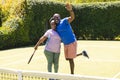Portrait of happy senior african american couple with rackets embracing on sunny grass tennis court Royalty Free Stock Photo