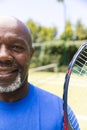 Portrait of happy senior african american man with tennis racket at sunny grass court, copy space Royalty Free Stock Photo