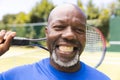 Portrait of happy senior african american man with tennis racket at sunny outdoor tennis court Royalty Free Stock Photo