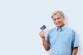 Portrait of happy senior asian man holding credit card and showing on hand smiling and looking at camera on isolated background f Royalty Free Stock Photo