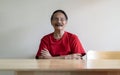 Portrait of happy senior Asian man sitting at wooden table with arm cross and looking at camera Royalty Free Stock Photo