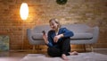 Portrait of happy senior caucasian lady sitting on floor and talking in videochat using smartphone in cozy home
