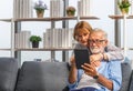 Portrait of happy senior couple in living room, Elderly woman and a man using tablet smartphone on cozy sofa at home, Happy family Royalty Free Stock Photo