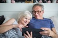 Happy senior couple lying in bed using tablet Royalty Free Stock Photo