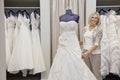 Portrait of a happy senior female adjusting wedding dress on mannequin in bridal store Royalty Free Stock Photo