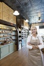 Portrait of a happy senior female spice merchant standing with arms crossed in store