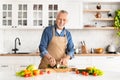 Portrait of happy senior man cooking food in kitchen at home Royalty Free Stock Photo
