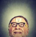 Portrait happy senior man in glasses with idea light bulb looking up. Royalty Free Stock Photo