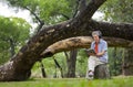 portrait happy senior man sitting on big log in summer park Royalty Free Stock Photo