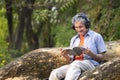 portrait happy senior man sitting on tree trunk in summer park Royalty Free Stock Photo