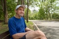 portrait happy senior man in sportswear sitting on bench in the forest park after running Royalty Free Stock Photo