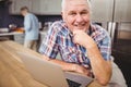 Portrait of happy senior man using laptop and woman working in kitchen Royalty Free Stock Photo