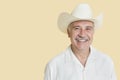 Portrait of happy senior man wearing cowboy hat over yellow background Royalty Free Stock Photo